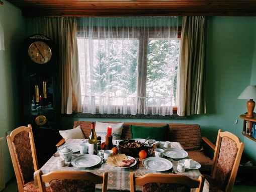 arranged table with chairs and plates near window