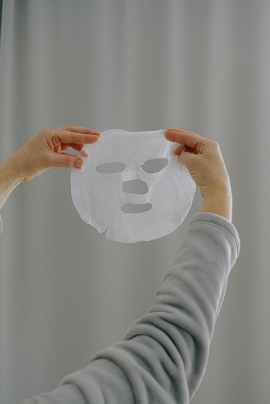 crop woman with sheet face mask